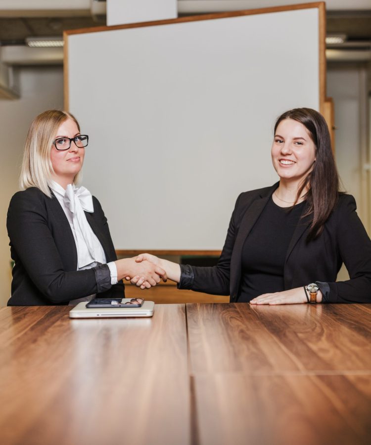 mujeres-sentado-tabla-sacudida-manos-sonriente